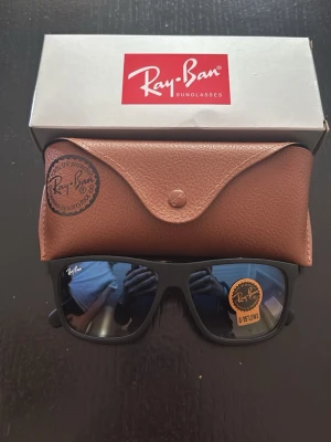 Ray-Ban solglasögon med fodral - Snygga Ray-Ban solglasögon levereras i originalförpackning med ett stilrent brunt fodral i skinn. Perfekt accessoar för att lyfta en enkel outfit med klassisk design som aldrig går ur tiden.