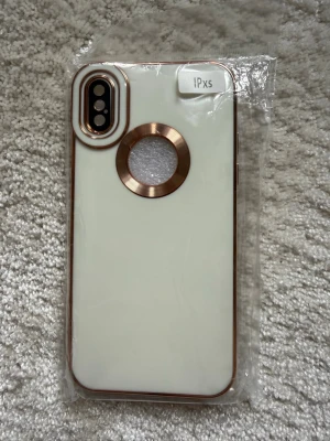 Ljusgrönt mobilskal med gulddetaljer iPhone Xs - Snyggt ljusgrönt mobilskal till iPhone Xs med guldfärgade kanter och ring runt Apple-loggan. Skalet har en öppning för kameran och är gjort i ett hårdare plastmaterial. Perfekt för dig som vill ha ett stilrent och elegant skydd till mobilen.