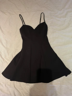 Klänning ZARA - Perfekt festklänning 💞En svart kort klänning med smala axelband och v-ringad urringning. Klänningen har en utsvängd kjol och figurnära passform upptill. Dragkedja i ryggen och justerbara band! Från Zara. 