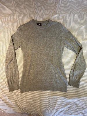 Grå stickad tröja från H&M - En grå stickad tröja från H&M. Rund halsringarna och ribbade muddar.