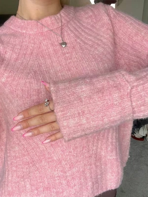 Rosa ribbstickad tröja - Mysig rosa stickad tröja med ribbade detaljer och rund hals. Tröjan har långa ärmar med breda muddar och en avslappnad passform💗💗