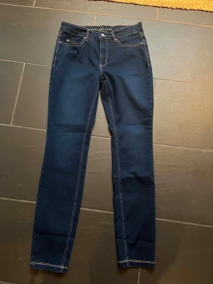 Jeans från MAC jeans - Säljer ett par mörkblå skinny jeans från MAC Jeans, modell Dream Skinny. Jeansen har klassisk femficksdesign, kontrastsömmar och är tillverkade i stretchigt material för en bekväm passform. Perfekta för dig som gillar en smal siluett. Helt nya med alla lappar på, inköpta för 1500kr säljs för 1000kr
