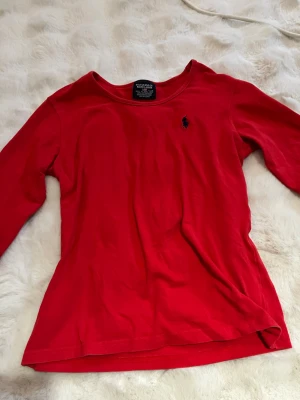 Röd långärmad topp från Ralph Lauren - Snygg röd långärmad topp från Ralph Lauren med rund halsringning och den klassiska loggan på bröstet💕står L men skulle säga att den sitter som S/M
