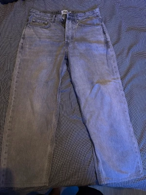Grå raka jeans från 157 - Säljer ett par grå jeans från 157 med rak passform och klassisk femficksdesign. Jeansen har hög midja och är tillverkade i ett slitstarkt denimtyg. Perfekta för en avslappnad och trendig look.