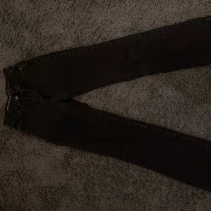 Svarta Regular Wide Jeans Waist 26/34 - Säljer ett par svarta jeans med regular wide passform och hög midja. Storlek waist 26 och längd 34. Klassisk femficksmodell med raka ben och knappgylf. Perfekta för en avslappnad och trendig look.