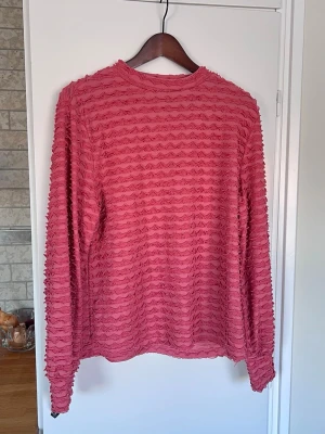 Roströd/gammelrosa långärmad topp med struktur, storlek L - Roströd/gammelrosa långärmad topp/blus med strukturerad yta. Rund halsringning och stretchig! Använd 2 gånger.