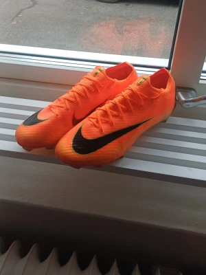 Nike orange fotbollsskor strl 44 - Säljer dessa skor då de inte riktigt passar mig. Köpta på unisport, nike mercurial vapor "deja vu", storlek 44. Originalkartong och påse medföljer. Använd 1 gång så de är typ fortfarande sprillans nya. 