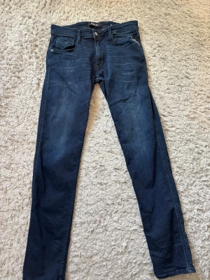 Mörkblå jeans från Replay - Snygga mörkblå jeans från Replay med klassisk femficksdesign och raka ben. Jeansen har en läderpatch med Replay-logga bak i midjan och är gjorda i slitstark denim. Perfekta för dig som gillar en tidlös och stilren look. Storlek 31:34