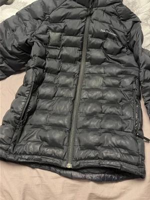 Svart dunväst från Peak Performance - Snygg svart dunväst från Peak Performance med quiltad design och dragkedja framtill. Västen har en sportig look och är perfekt för kyliga dagar. Klassisk passform och diskret logga på bröstet.