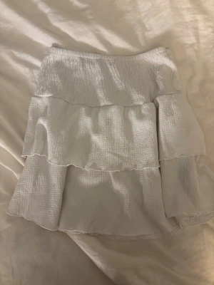 Vit volangkjol från Gina Tricot - Supersöt vit kjol från Gina Tricot med flera lager volanger och resår i midjan. 