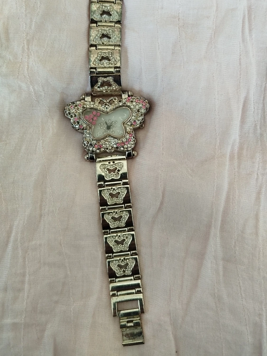 Silverfärgad klocka med fjäril och stenar