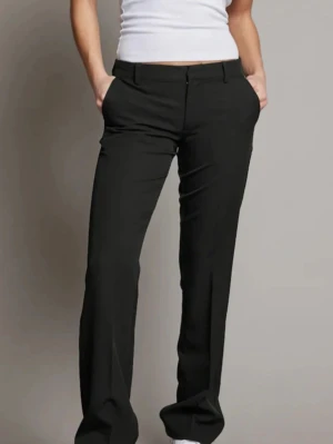 Svarta lågmidjade kostymbyxor - Säljer de populära kostymbyxorna från kokbok! Snygga svarta lågmidjade kostymbyxor med utsvängda ben och klassisk passform. Byxorna har fickor fram och bälteshällor i midjan. Perfekta till en stilren look och passar till många olika outfits. 🥰