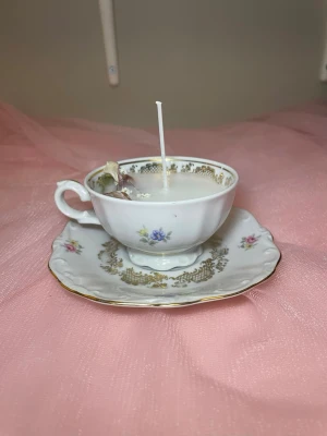 Doftljus med vaniljdoft i en tekopp med fat i en blommig design  - Det här ljuset är gjort av återanvändbara material. Tekoppen är köpt secondhand och stearinet är från kyrkor som tänkte slänga det. Det här ljuset har en svag doft utav vanilj, så känsliga även kan använda det. Det här ljuset har även torkade blommor på som dekoration. 