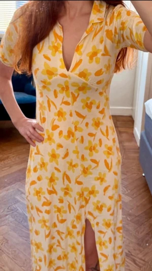 Blommig gul klänning midiklänning från ASOS DESIGN - Snygg midiklänning från ASOS DESIGN med blommigt mönster i gult och orange på vit botten. Klänningen har kort ärm, krage, djup v-ringning och slits framtill. Perfekt för varma dagar och somriga vibes. Har en skjortkrage. Fint skick. Slutar en bit nedanför knäna.