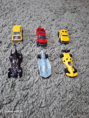 Samling leksaksbilar i metall - Sex små leksaksbilar i olika färger och former. Blandningen inkluderar sportbilar, en Batmobil, en gul formelbil och en blå futuristisk bil. Bilarna är tillverkade i metall och plast, och har detaljerade designer. Perfekt för samlare eller lek.