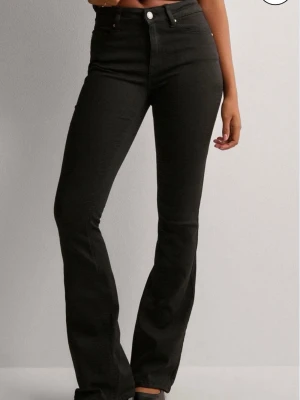 Svarta jeans - Snygga svarta bootcut jeans med medelhög midja och klassisk femficksdesign. Jeansen har en smickrande passform som sitter tight upptill och släpper ut vid benen. Perfekta till sneakers eller boots och tillverkade i stretchigt denimtyg för extra komfort. Köpta från Nelly men är från vero Moda