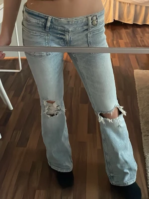 Ljusblå slitna jeans med hål från Gina Tricot - Säljer ett par ljusblå jeans med låg midja och raka ben. Jeansen har stora slitningar och hål vid båda knäna. Nypris är 399kr, nästan helt oanvända, använt 2 gånger. Rätt så små i storleken (M 14+)