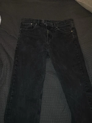 Svarta slim fit jeans - Säljer ett par svarta slim fit jeans med klassisk femficksdesign. Jeansen har en smal passform och är tillverkade i ett mjukt denimtyg som sitter snyggt. Perfekta för dig som gillar en stilren och enkel look.