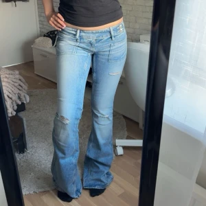 Ljusblå bootcut jeans med slitningar - Säljer ett par ljusblå bootcut jeans med låg midja och slitna detaljer på låren. Midjemått: 36cm rakt över, innerbenslängd: 83cm. Har använts bara en gång 💕