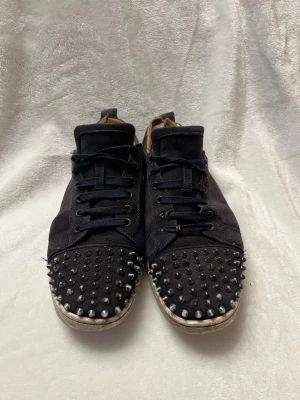 Svarta Louboutin sneakers med nitar - Tjena säljer dessa slitna Loubs i str 45, går fortfarande att använda har inte läckt in under min ägodel!! Skriv för fler bilder eller intresse