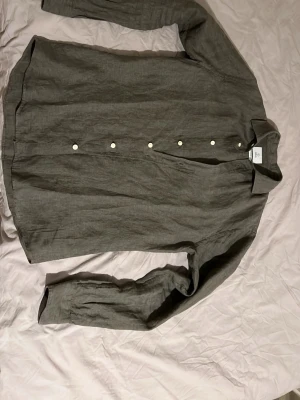 Grön linnén skjorta - Hej, säljer min skjorta då jag inte använder den. Använd typ 2 gånger. Säljer pga av att jag inte gillar passformen. Modellen är 187cm och väger 73kg