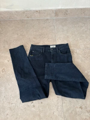 Tiger of Sweden jeans - Snygga mörkblå jeans från Tiger of Sweden med klassisk femficksdesign och raka bakfickor. Jeansen har en smal passform och är tillverkade i mjukt bomullsmaterial med stretch. Perfekta för dig som gillar stilrena och tidlösa jeans. Helt nytt skick!!! Stl 28/34