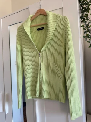 Y2k Ljusgrön ribbstickad ziptröja STUTS - Snygg ljusgrön ribbstickad tröja från STUTS med dragkedja framtill och bred krage. Tröjan har långa ärmar och två snedställda fickor. Perfekt för dig som gillar en fräsch och trendig look.