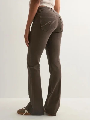 Bruna bootcut jeans från NELLY - Säljer ett par bruna bootcut jeans från Nelly med klassiska kontrastsömmar och broderad bakficka. Jeansen har normal midja, fem fickor och stängs med knapp och dragkedja. Perfekta för en avslappnad och trendig look. Använder inte längre 