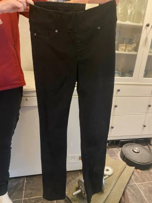 Svarta skinny jeans med hög midja - Säljer ett par svarta skinny jeggings med hög midja och låtsasfickor fram och riktiga bak. Jeggings har smal passform och raka ben, perfekta till en avslappnad eller trendig look. Materialet känns stretchigt och bekvämt.