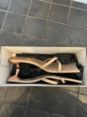 Beige sandaler med klack från Topshop - Snygga beige pumps från Topshop med fyrkantig tå och smala remmar med spänne. Klacken skulle jag gissa är mellan 3-4 cm och skon har en modern, minimalistisk design. Perfekt för dig som gillar stilrena och trendiga skor. Testade en gång ute! Köpta för 929kr 