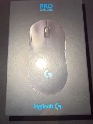 Logitech G Pro Wireless Gamingmus - Trådlös gamingmus från Logitech, modell G Pro Wireless. Svart färg med stilren design och logotyp i vitt. Ergonomisk form med texturerade sidor för bättre grepp. Perfekt för gaming och snabb respons tack vare avancerad sensor. Grip tape