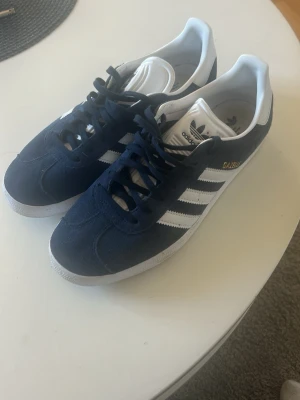 Adidas Gazelle mörkblå sneakers - Säljer ett par klassiska Adidas Gazelle sneakers i mörkblå mocka jag har använt dom 1 gång så inprincip helt nya, skriv för fler bilder om önskas:)