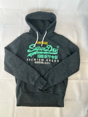 Mörkgrå Superdry hoodie - En riktigt fet superdry! Sitter som M och passar perfekt och har fint skick. | Skick:9/10 | modellen är 185cm lång‼️ Mått armhåla-armhåla 53cm och armhåla-slut 45cm. Pris 599 men kan diskuteras😁☺️🤩