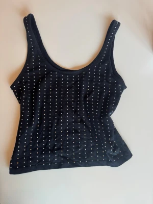 Svart linnetopp med glittriga detaljer - Svart paljettopp från BikBok i storlek M ✨ Glittrar superfint i ljuset och sticker verkligen ut – perfekt när du vill känna dig lite extra snygg! Passar lika bra till fest som till en kväll ute med vänner.  Sitter bra på och är enkel att matcha med både jeans och kjol. Använd få gånger, så den är i jättebra skick! Pris kan diskuteras!