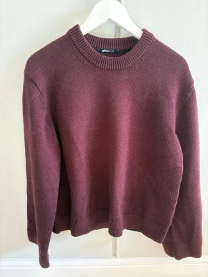 Vinröd stickad tröja från Gina Tricot - Mysig vinröd stickad tröja från Gina Tricot med rund halsringning och ribbade muddar vid hals, ärmslut och nederkant. Tröjan är endast använd några fåtal gånger så tröjan är som ny! 