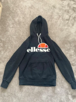 Fin Svart Ellesse hoodie 🫶🏻 - Säljer en jätte fin hoodie från Ellesse i storlek M, men den är liten i storleken. Super bra skick, och är super gosig. Den är inte kol svart utan lite blekt men inget som syns ❣️