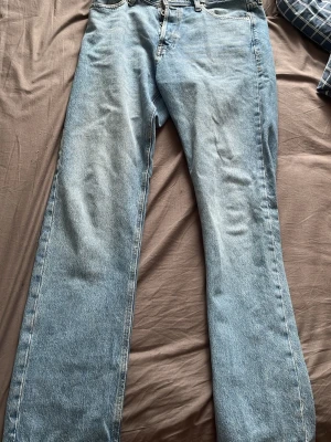Ljusblå raka jeans från Jack & Jones - Säljer ett par ljusblå jeans från Jack & Jones med rak passform och klassisk femficksdesign. Jeansen har en snygg tvättad look och är tillverkade i slitstark denim. Perfekta för en avslappnad och trendig stil. Storleken är 31/32