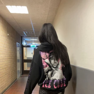 Svart hoodie med Ice Cube-tryck💙💜🩷 - Säljer en svart hoodie med stor grafisk print på ryggen och texten 'ICE CUBE' i lila/rosa nyans. Hoodien har huva och tryck även på ena ärmen, där det står ”Today was a good day” . Perfekt för dig som gillar streetwear och vill sticka ut med en unik design.💙💜🩷