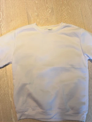 Vit sweatshirt från Stone Island - Säljer en clean vit sweatshirt från Stone Island med klassisk rund hals och ribbade muddar. Tröjan har den ikoniska Stone Island-loggan på ärmen. Perfekt för dig som gillar stilrena och trendiga plagg.