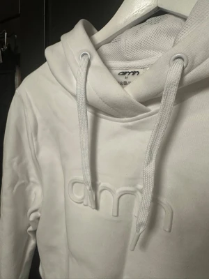 Vit cropped kort hoodie från Aimn - Säljer en vit cropped kort hoodie från aimn med broderad logga framtill. Hoodien har dragsko i huvan och är tillverkad i mjukt sweatshirtmaterial. Perfekt för en chill och trendig look.