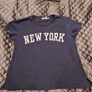 Tshirt med tryck - Blå T-shirt med snyggt tryck och lite slits på sidorna. Gott skick