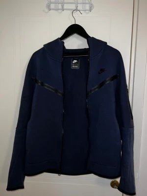Nike Tech Fleece Dress Blå - Helt ny Nike Tech Fleece dress i färgen ”Navy Blue”. Väldigt bra pris då nypriset ligger på 2000+ kr.
