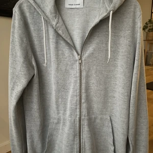 Samsøe Samsøe Zip Hoodie - Säljer denna grå tunna zip hoodien från Samsøe Samsøe. Stl M men även passar S. Toppen julklapp🎁 Cond 7/10  ganska bra skick förutom ena snöret som har tappat toppen. Bara att meddela vid intresse eller frågor!