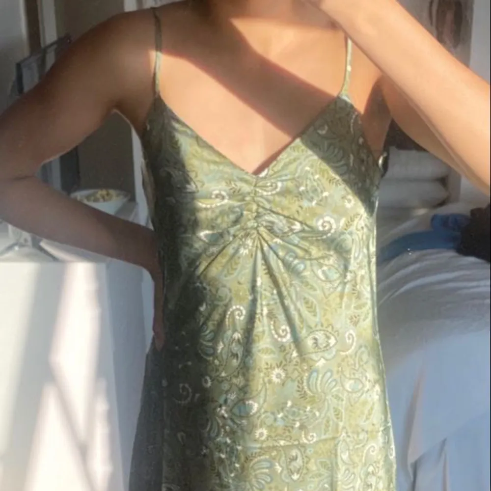 Säljer min helt oanvända gröna satin klänning med mönster då den aldrig kommit till användning !💚. Klänningar.
