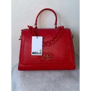 Röd cross body/handväska från Love, Moschino. Axelrem medföljer. Aldrig använd och i nyskick. Köpt på Zalando 2021.    Ca 26x20x10 cm stor❤️  Kan frakta eller mötas i Uppsala☁️