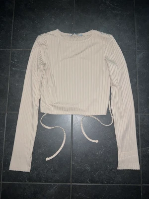 Beige topp med öppen rygg  - Säljer en beige topp med öppen rygg från NA-KD storlek xs, pris 150kr