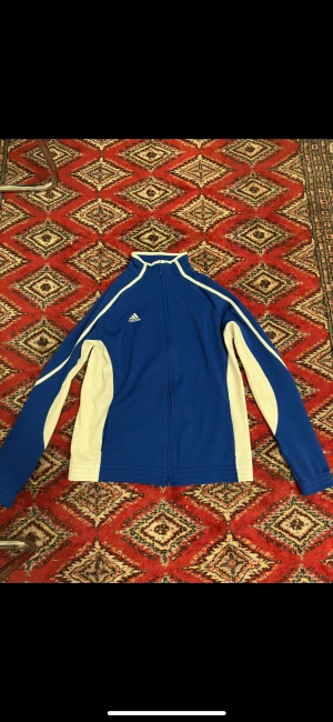 Vintage Adidas Tracksuit 90s - En vintage Adidas tracksuit från 90-talet, blå vit men ser lite gul ut pågrund utav av lampan jag har. Storleken är M men sitter som S