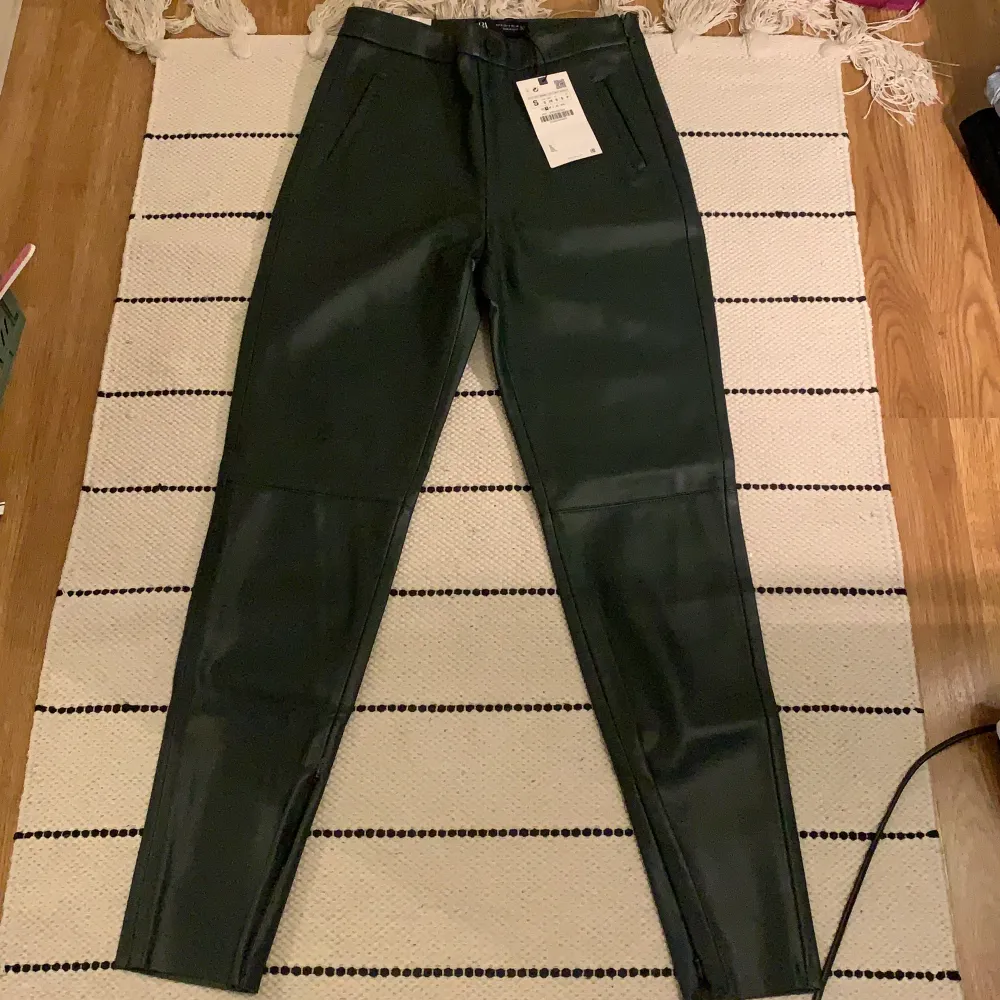 Mörkgröna skinnleggings från Zara, storlek S. Ej använda, prislapp fortfarande kvar. Högmidjade, dragkedja vid sidan.. Jeans & Byxor.