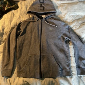 Lacoste zip up - As fet Lacoste zip up! Kondition 7/10. Har en liten fläck på ena ärmen. Aldrig försökt att få bort så ingen aning om den är permanent eller inte. Size: US L men passar som en S. Pris 400. Pris kan diskuteras vid snabb affär. 