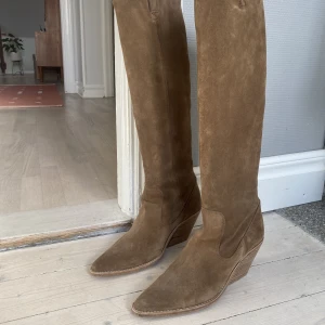 Cowboystövlar 39 från bronx - Säljer mina mockaboots från bronx i storlek 39!! Använda 2 gånger så i princip i nyskick! De är väldigt bekväma att gå i och slutar lite under knäna. Färgen heter "dark natural". Nypris 2500. Köparen står för frakten! Skickar spårbar frakt via postnord.